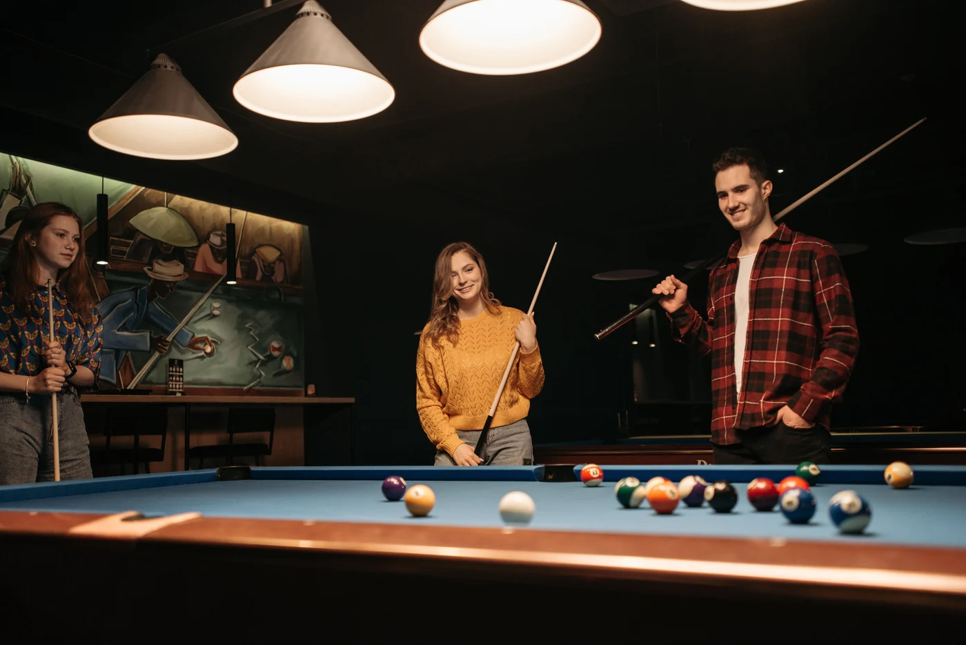 Friends playing pool around a blue billiards table